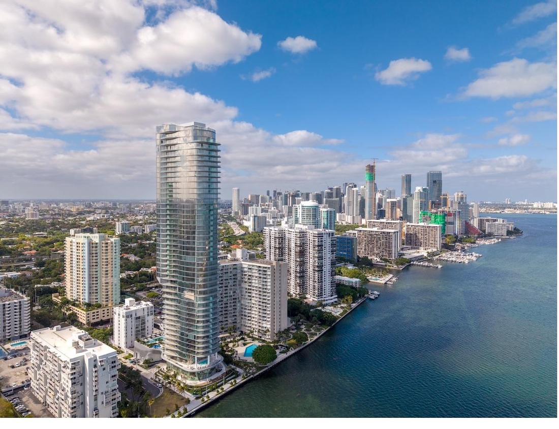Aerial view of a Brickell waterfront residential tower on Biscayne Bay with the downtown Miami skyline beyond